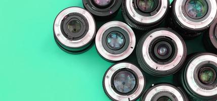 Several photographic lenses lie on a bright turquoise background. Copy space photo