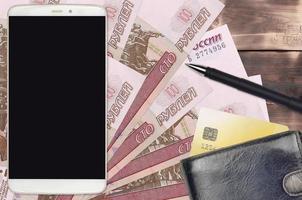 Billetes de 100 rublos rusos y smartphone con monedero y tarjeta de crédito. pagos electrónicos o concepto de comercio electrónico. compras y negocios en línea con dispositivos portátiles foto