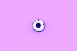 Single small plastic donut lies on a pastel colorful background. Flat lay minimal composition. Top view photo