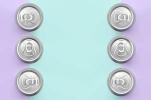 Many metallic beer cans on texture background of fashion pastel violet and blue colors paper in minimal concept photo