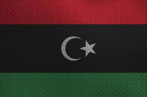 Libya flag depicted in paint colors on old brushed metal plate or wall closeup. Textured banner on rough background photo