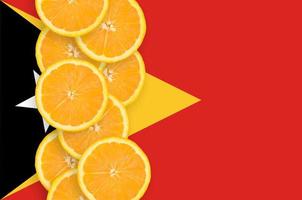 Timor Leste flag and citrus fruit slices vertical row photo