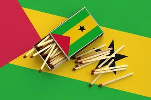 Sao Tome and Principe flag is shown on an open matchbox, from which several matches fall and lies on a large flag photo