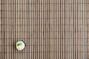 Sushi roll lie on a bamboo straw serwing mat. Traditional Asian food. Top view. Flat lay minimalism shot with copy space photo