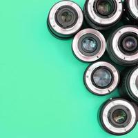 Several photographic lenses lie on a bright turquoise background. Copy space photo