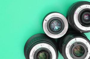 Several photographic lenses lie on a bright turquoise background. Copy space photo