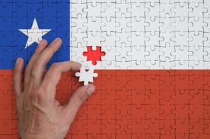 Chile flag is depicted on a puzzle, which the man's hand completes to fold photo