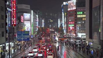 Shinjuku, Tóquio, Japão 2019-11-22. as pessoas atravessam a rua enquanto chove e há carros na estrada. na cidade de Shinjuku, Tóquio, Japão. video
