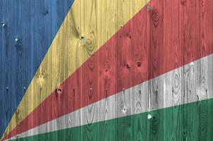 Seychelles flag depicted in bright paint colors on old wooden wall. Textured banner on rough background photo