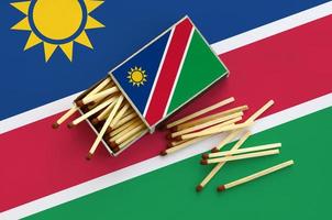 Namibia flag is shown on an open matchbox, from which several matches fall and lies on a large flag photo