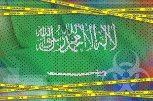 Saudi Arabia flag and Covid-19 quarantine yellow tape. Coronavirus or 2019-nCov virus concept photo