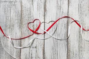 Red and white ribbon hearts for valentines day on wooden background photo