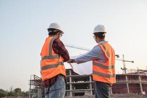 dos ingenieros asiáticos que trabajan en el sitio de un gran proyecto de construcción, gente tailandesa, trabajan horas extra en el sitio de construcción, equipo de ingenieros discus en el sitio foto