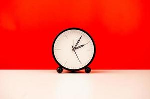 white alarm clock isolated on red background photo