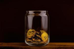 gold coin in glass bottle on black scene, money and gold saving concept photo