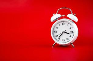 white alarm clock on red background time concept photo