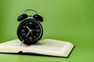black alarm clock Put on an open book, reading ideas and reading time. photo