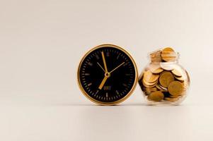 Golden alarm clock and coin in glass bottle, money saving idea. photo