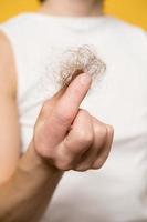 Hair loss. Female hand holds a bun of hair. Close-up. photo