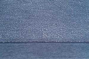 Pellets on textured blue fabric background. Reverse side of old clothes with white roll. Copy space. Top view. photo
