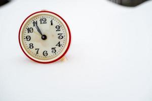 Old mechanical alarm clock in the snow, on a winter day. Copy space. photo