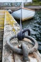 Mooring ring on the pier, sailing boat is tied with knot in the background photo