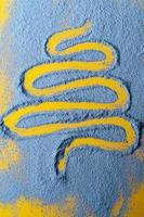 el abeto, símbolo del año nuevo y la navidad, se dibuja sobre un polvo azul sobre un fondo amarillo. concepto de vacaciones. vista superior. foto