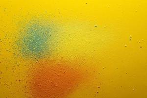 Multicolored powder, orange, green and yellow, scattered on a bright background. Copy space. Abstract texture. Top view. photo