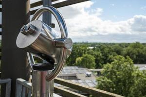 Tower viewer with city view, rooftops, green trees and blue sky with clouds. photo