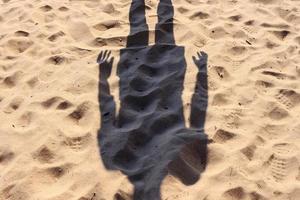 Headless human shadow on a sandy beach, on a sunny summer day. photo