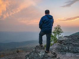 caminante gordo asiático con la luz del atardecer en el acantilado de yeabmek parque nacional de la montaña phu kradueng en la ciudad de loei tailandia. parque nacional de la montaña phu kradueng el famoso destino de viaje foto