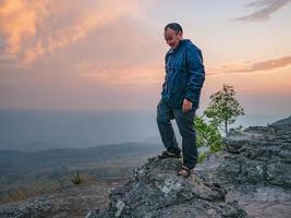caminante gordo asiático con la luz del atardecer en el acantilado de yeabmek parque nacional de la montaña phu kradueng en la ciudad de loei tailandia. parque nacional de la montaña phu kradueng el famoso destino de viaje foto