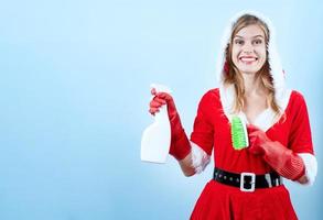 closeup of caucasian happy woman wearing santa clothes and cleaning gloves,holding cleaning spray and brush