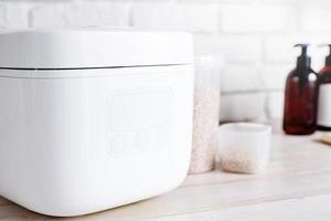 Electric rice cooker on wooden counter-top in the kitchen, closeup of display photo