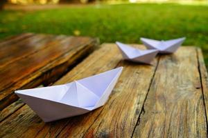 Origami, white paper boat isolated on a wooden floor.  Paper boats mean walking.  feeling of freedom  leadership photo