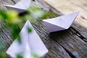 Origami, white paper boat isolated on a wooden floor.  Paper boats mean walking.  feeling of freedom  leadership photo