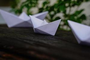 Origami, white paper boat isolated on a wooden floor.  Paper boats mean walking.  feeling of freedom  leadership photo