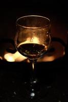 Glass of wine against the backdrop of a bonfire in the fireplace photo