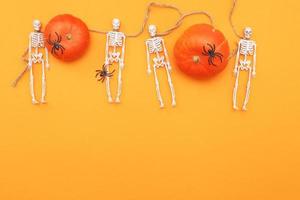 Halloween pumpkin with skeletons and black spiders on orange background. photo