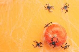 calabaza de Halloween con tela de araña y arañas negras sobre fondo naranja. foto