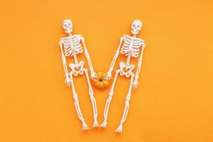 skeletons with pumpkin on orange background. halloween concept photo