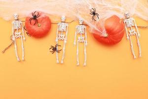 calabaza de halloween con tela de araña, esqueleto y arañas negras sobre fondo naranja. foto