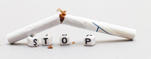 broken cigarette with the word stop on gray background close. stop smoking concept. banner photo