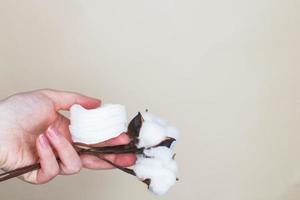 Hands of a woman holding cotton swabs on a beige background photo