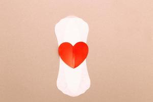 Feminine sanitary pad with a red heart on pink background photo