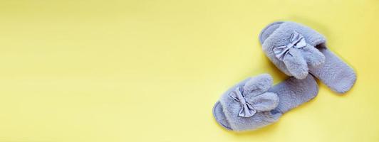 Pair of stylish soft slippers on yellow background, flat lay. copy space for text. banner photo