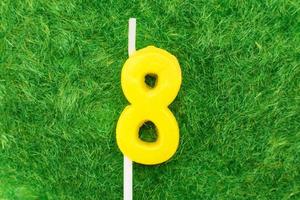 candle in the form of number 8 on the green grass background, a place for a greeting text photo