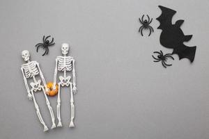 skeletons with pumpkin, bat and black spiders on a grey background. halloween concept photo