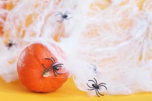 calabaza de Halloween con tela de araña y arañas negras sobre fondo naranja. foto