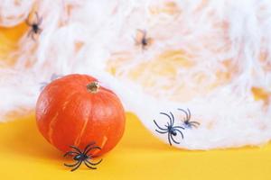 calabaza de Halloween con tela de araña y arañas negras sobre fondo naranja. foto